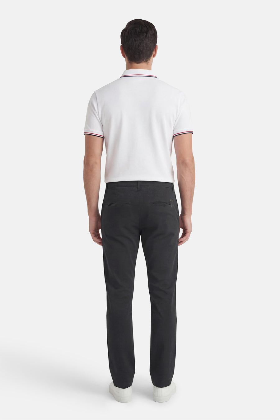 Chino noir de JACK & JONES JEANS INTELLIGENCE avec poches arrière passepoilées, porté avec un polo blanc à rayures.