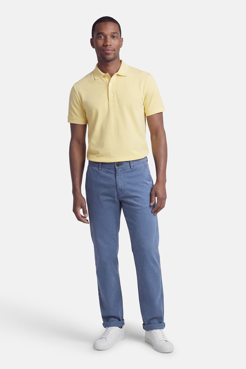 Blauwe chino van JACK & JONES JEANS INTELLIGENCE, gedragen met een gele polo en witte sneakers.