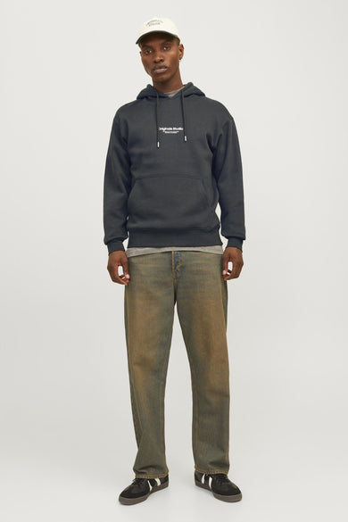 Dark green hooded sweatshirt with white chest logo by Originals Studio, worn with olive jeans and black sneakers, full-length front view