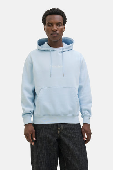 Sweat à capuche bleu d'ORIGINALS BY JACK & JONES, avec cordon de serrage et poche kangourou, porté avec un pantalon foncé