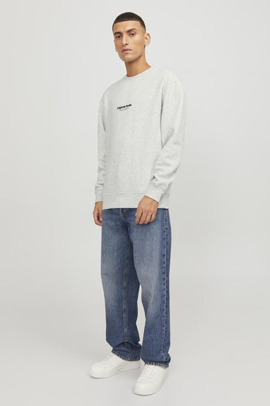 Sweat-shirt écru de Originals by JACK & JONES, avec inscription sur le devant, porté avec un jean bleu et des baskets blanches.