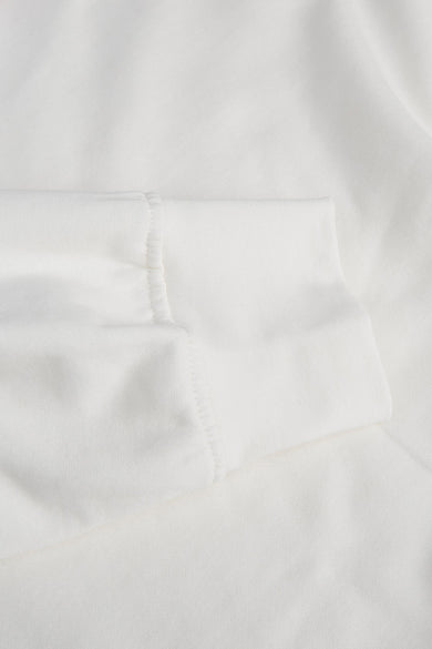 White crewneck sweatshirt with soft cotton texture and clean ribbed sleeve cuff, close-up view