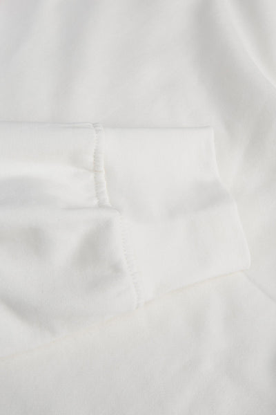 White crewneck sweatshirt with soft cotton texture and clean ribbed sleeve cuff, close-up view