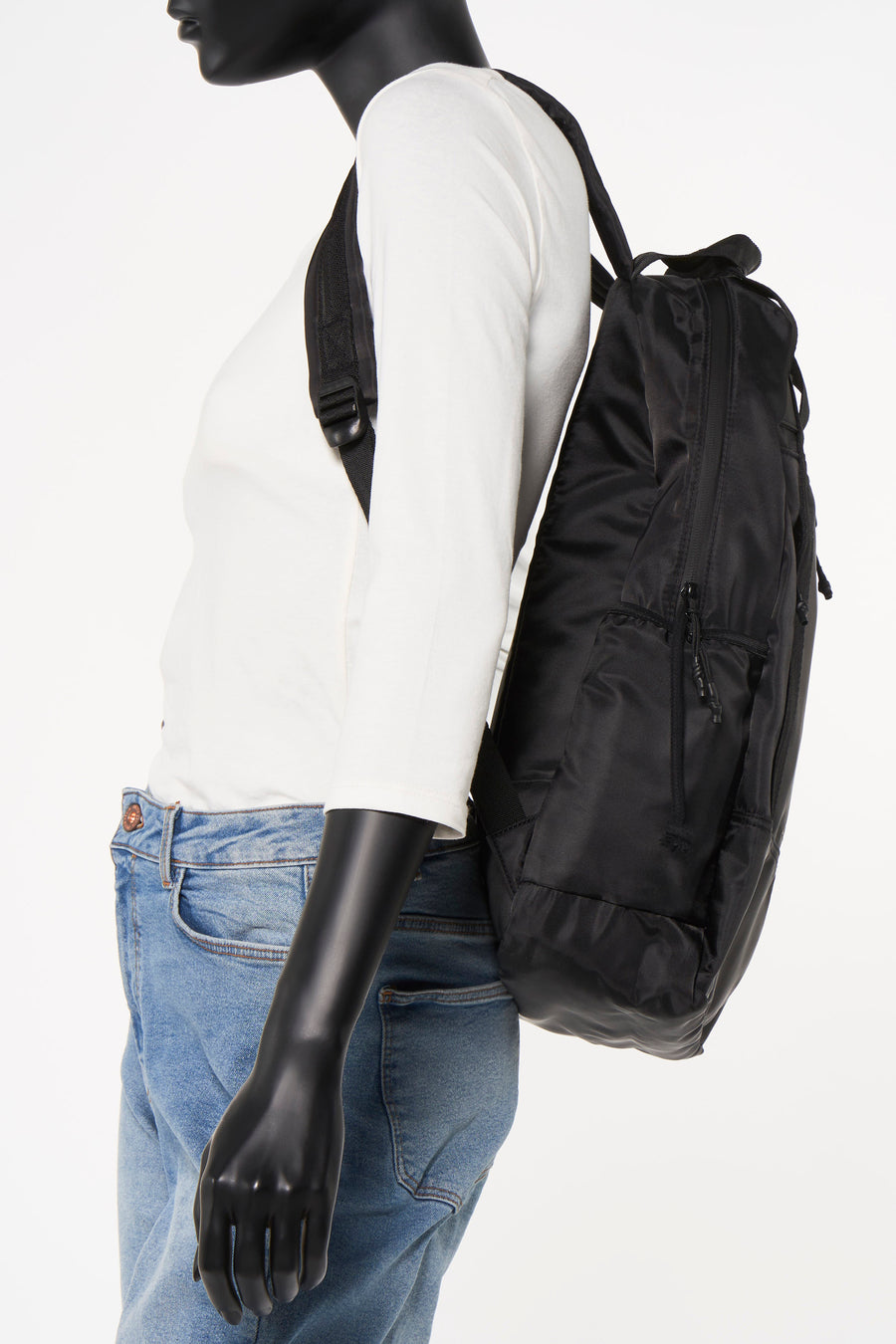 Zwarte rugzak van ACCESSORIES BY JACK & JONES, gedragen met een wit T-shirt en een blauwe jeans, zijwaarts bekeken.