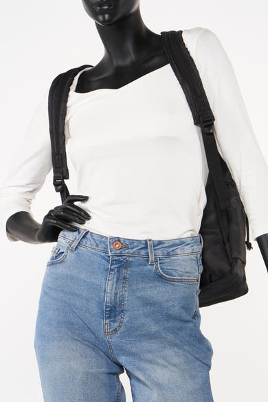 Zwarte rugzak van Accessories by Jack & Jones, gedragen met een spijkerbroek en een witte top met lange mouwen.
