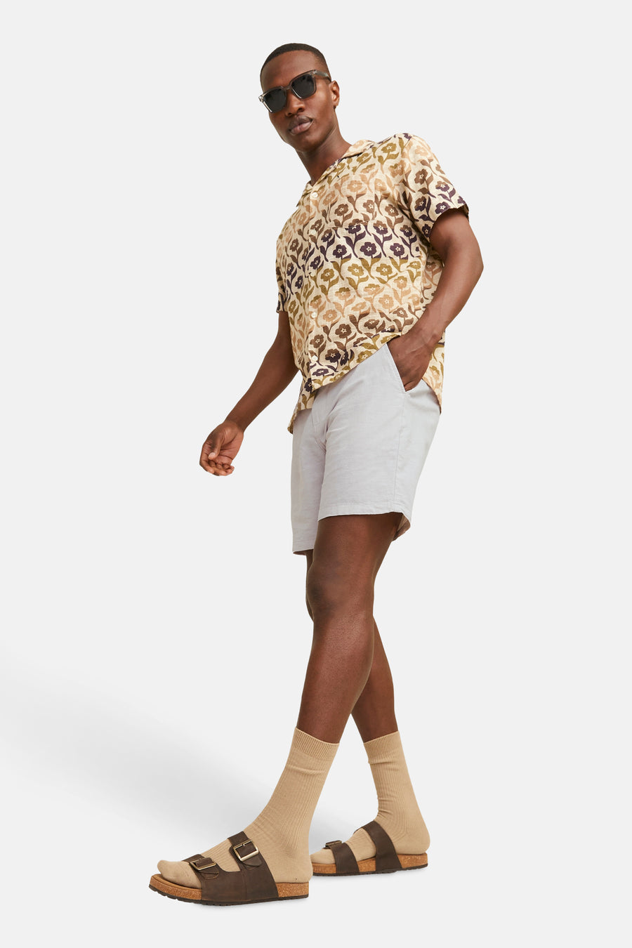 Short beige JACK & JONES JEANS INTELLIGENCE porté avec une chemise à motif floral et des sandales avec des chaussettes.