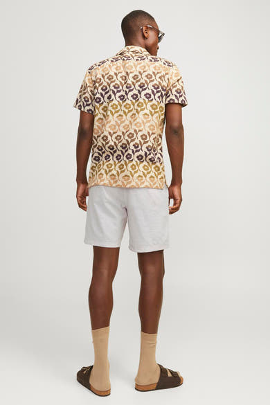 Short beige JACK & JONES JEANS INTELLIGENCE, porté avec une chemise à motifs floraux, des chaussettes et des sandales.