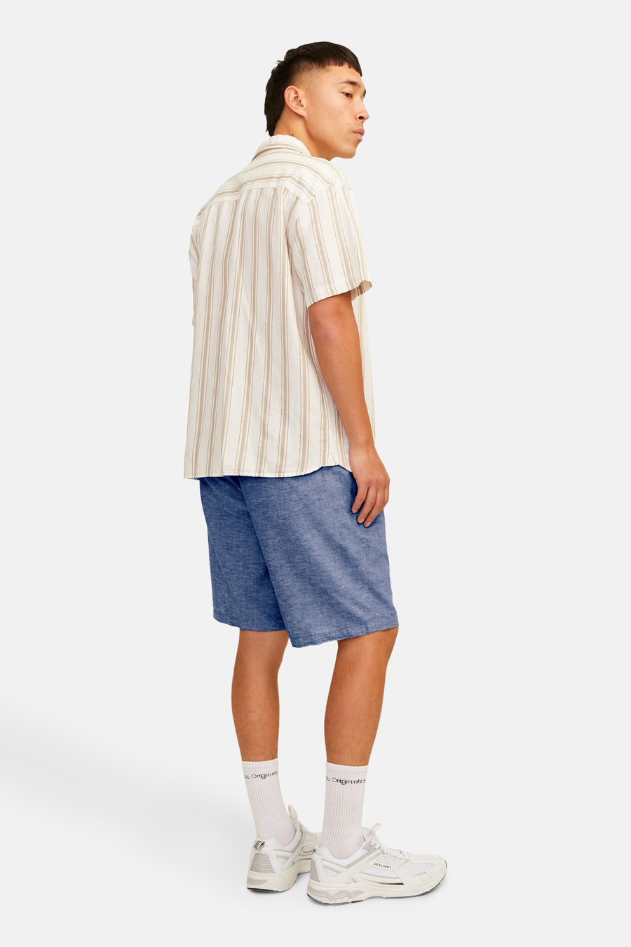 Short bleu de JACK & JONES JEANS INTELLIGENCE, porté avec une chemise rayée et des chaussures de sport blanches.