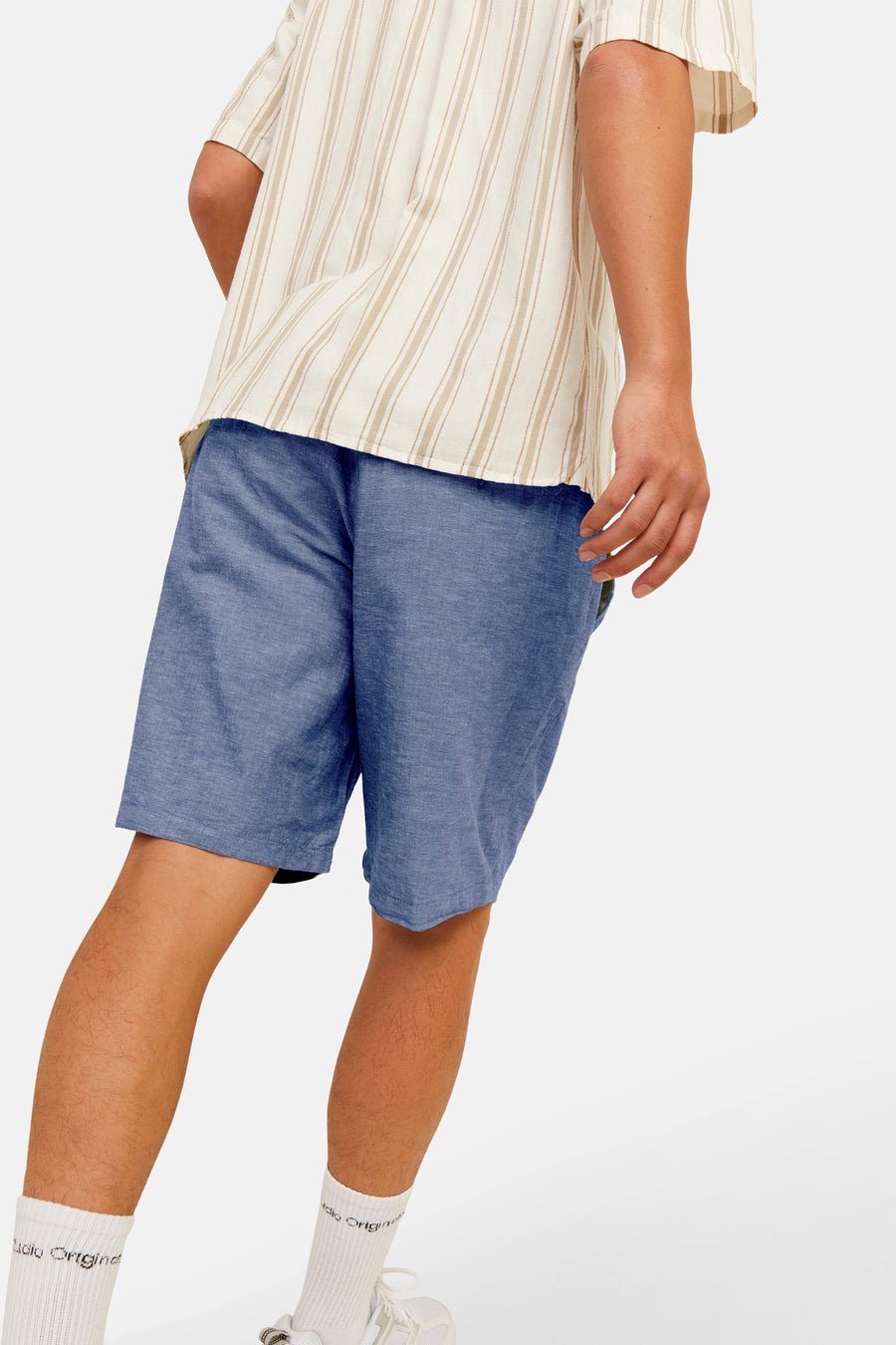 Short bleu par JACK & JONES JEANS INTELLIGENCE, coupe décontractée, porté avec une chemise rayée.
