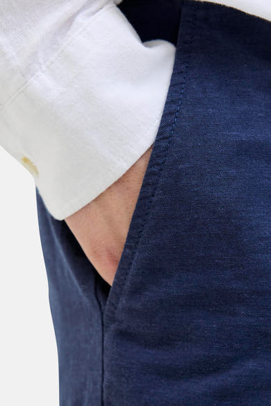 Short bleu de JACK & JONES JEANS INTELLIGENCE, avec une main dans la poche et une chemise blanche visible.
