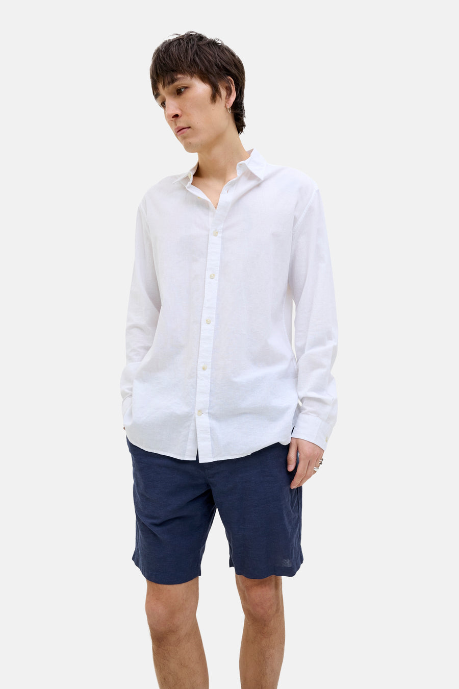 Short bleu JACK & JONES JEANS INTELLIGENCE porté avec une chemise blanche, modèle avec les mains dans les poches.