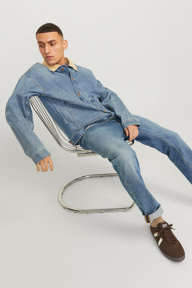 Jack & Jones Jeans Intelligence middellange blauwe rechte jeans, gedragen met een spijkerjasje op een metalen stoel.