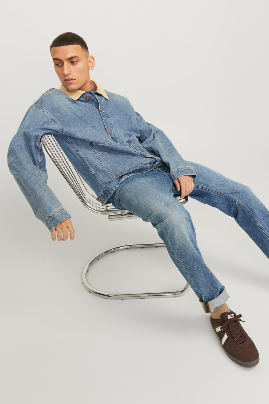 Jack & Jones Jeans Intelligence middellange blauwe rechte jeans, gedragen met een spijkerjasje op een metalen stoel.