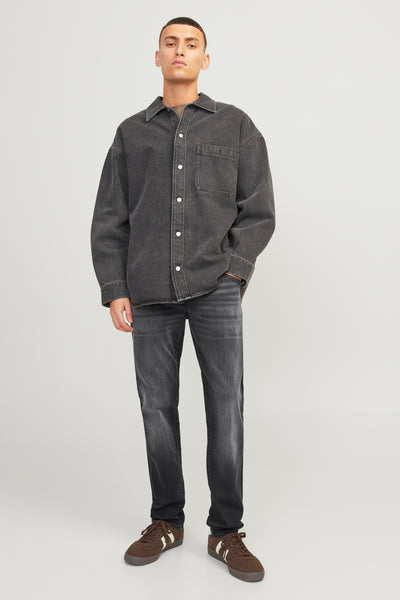 Jean slim en denim noir de Jack & Jones Jeans Intelligence, porté avec une chemise et des chaussures marron.