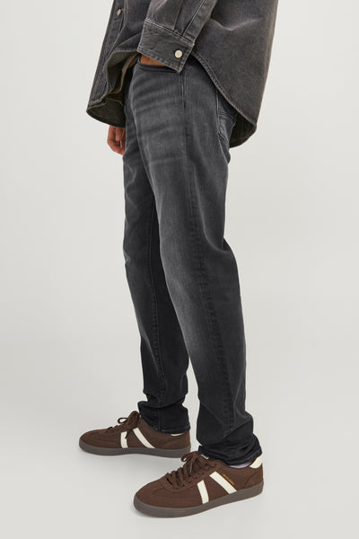 Jean slim en denim noir par JACK & JONES JEANS INTELLIGENCE, porté avec des chaussures de sport marron à rayures blanches.