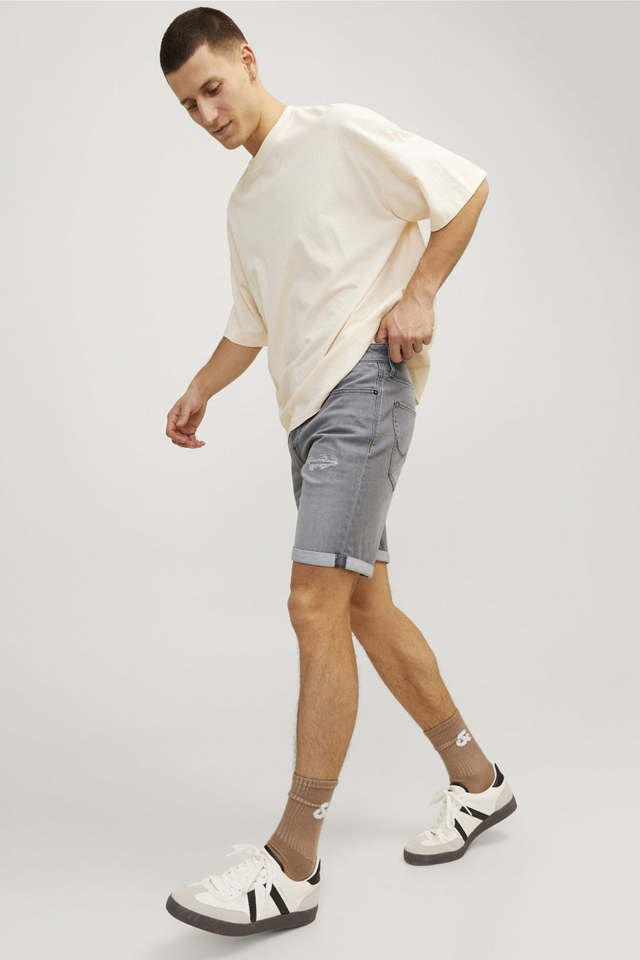 Korte spijkerbroek in grijs van JACK & JONES JEANS INTELLIGENCE, gedragen met een beige T-shirt en witte sneakers.