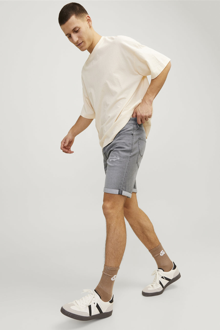 Korte grijze denim van JACK & JONES JEANS INTELLIGENCE met omgeslagen zomen, gedragen met een beige T-shirt en sneakers.
