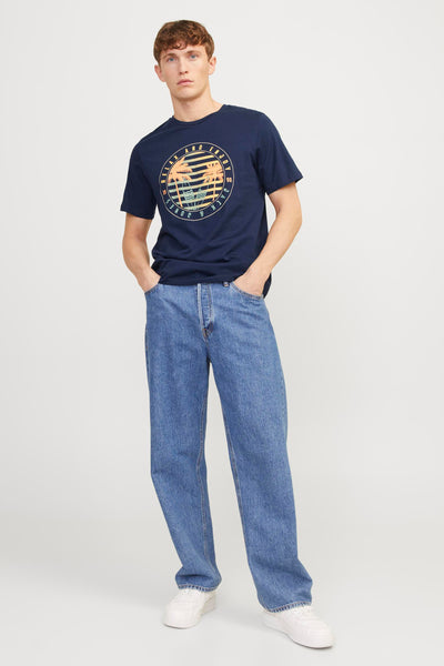 Navy blue short-sleeve t-shirt with circular tropical graphic, worn by model in jeans and white sneakers, front view