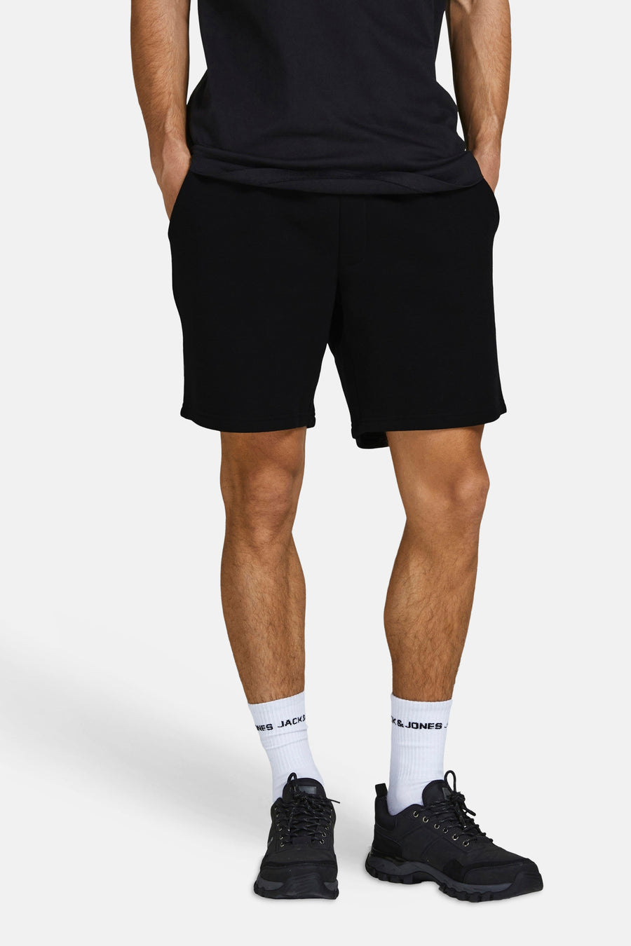 Korte zwarte broek van JACK & JONES JEANS INTELLIGENCE gedragen met witte sokken en zwarte sportschoenen.