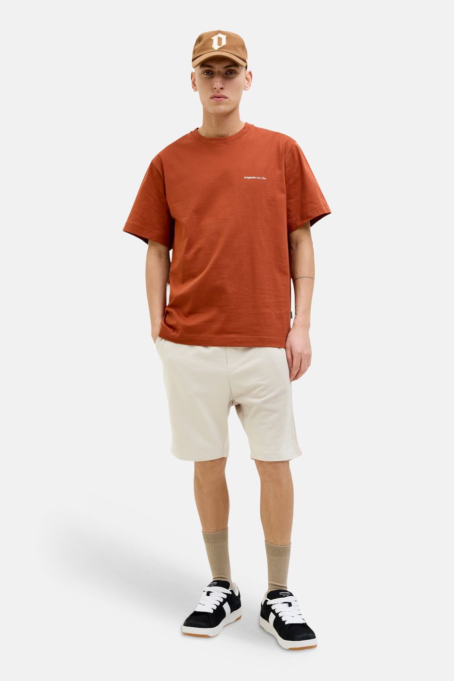 Korte ecru joggingbroek van joggingstof van JACK & JONES JEANS INTELLIGENCE, gedragen door een man met een T-shirt en sneakers.