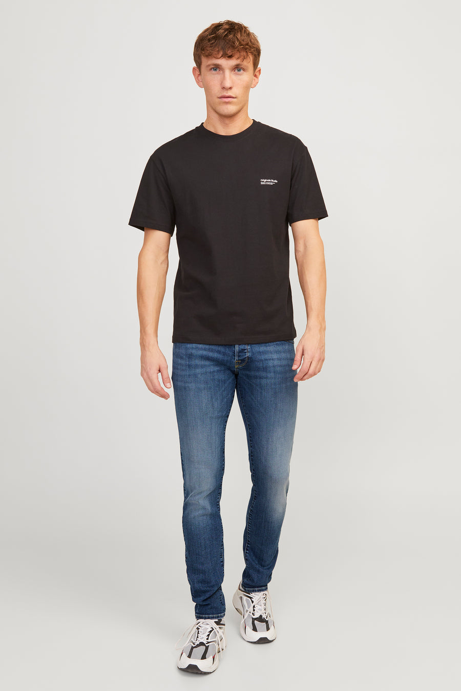 Middelblauwe slim fit jeans van JACK & JONES JEANS INTELLIGENCE, gedragen met een zwart T-shirt en witte sneakers.
