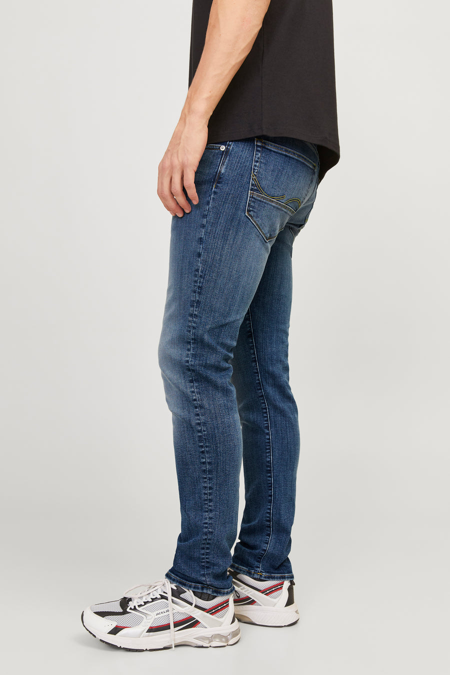 Middelblauwe spijkerbroek van JACK & JONES, gedragen met een zwart T-shirt en witte sneakers.