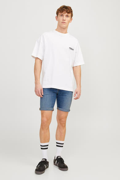Short en denim bleu moyen de JACK & JONES JEANS INTELLIGENCE, avec ourlet retroussé, porté avec des chaussettes rayées.
