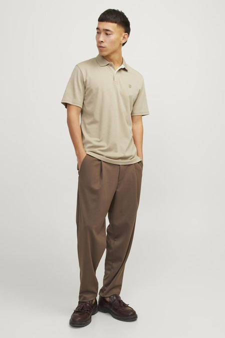 Polo beige de PREMIUM by JACK & JONES, porté avec un pantalon marron ample et des chaussures en cuir.
