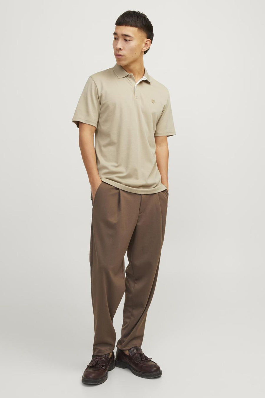 Polo beige de PREMIUM by JACK & JONES, porté avec un pantalon marron ample et des chaussures en cuir.