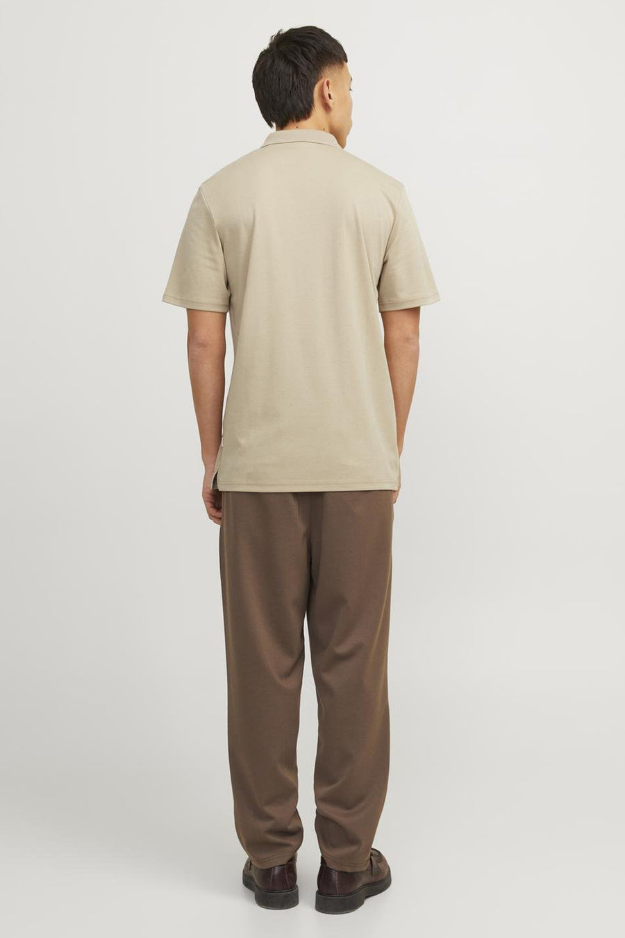 Polo beige de PREMIUM by JACK & JONES, porté avec un pantalon marron et des chaussures en cuir marron.