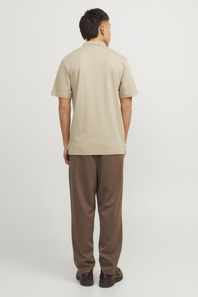 Beige polo van PREMIUM by JACK & JONES, van achteren gezien, gedragen met een bruine broek en schoenen.