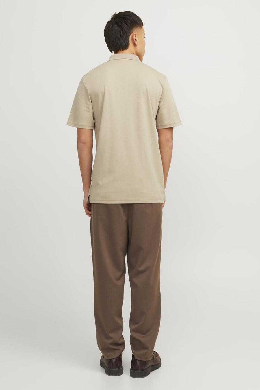 Beige polo van PREMIUM by JACK & JONES, van achteren gezien, gedragen met een bruine broek en schoenen.