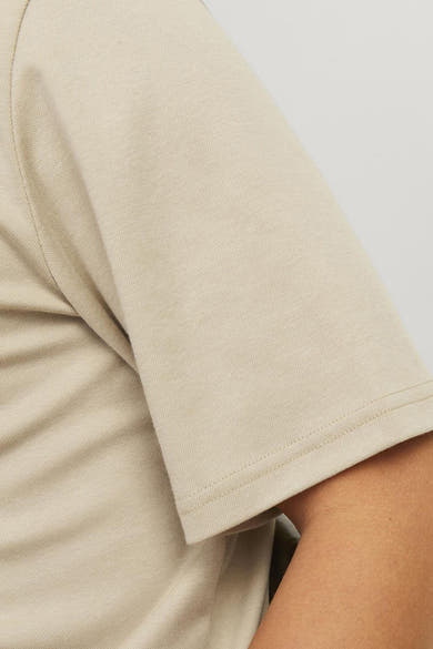 Beige polo van PREMIUM by JACK & JONES, met zichtbare textuur van de stof en de naad van de mouw.