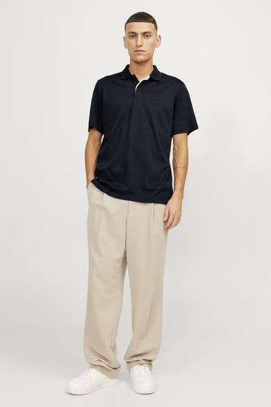 Marineblauwe polo van PREMIUM by JACK & JONES, gedragen met een beige broek en witte sneakers.