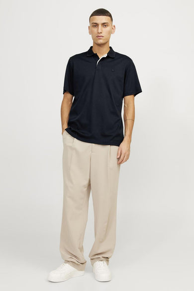 Marineblauwe polo van PREMIUM by JACK & JONES, gedragen met een beige broek en witte sneakers.