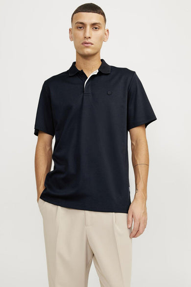 Marineblauwe polo van PREMIUM by JACK & JONES, met contrasterende details op de kraag, gedragen met een beige geplooide broek.