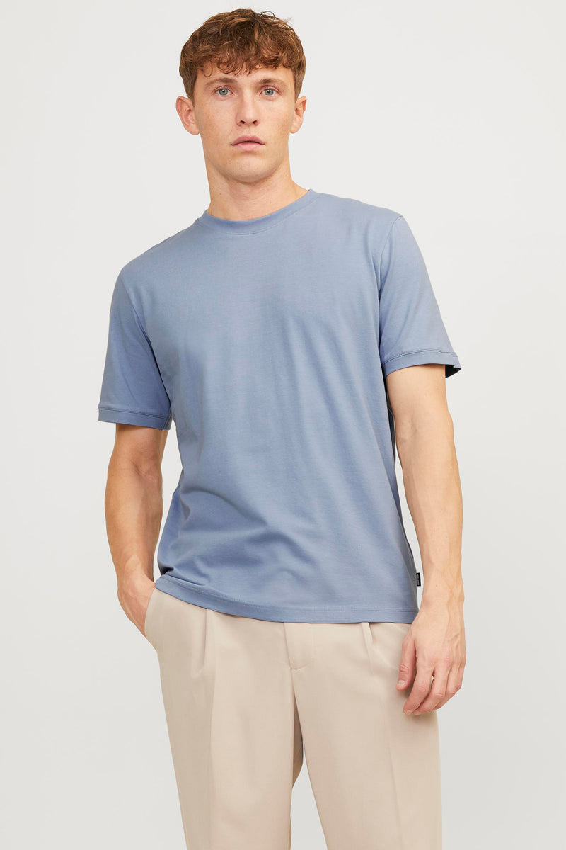 T-shirt bleu PREMIUM by JACK & JONES, porté avec un pantalon beige et les mains dans les poches.
