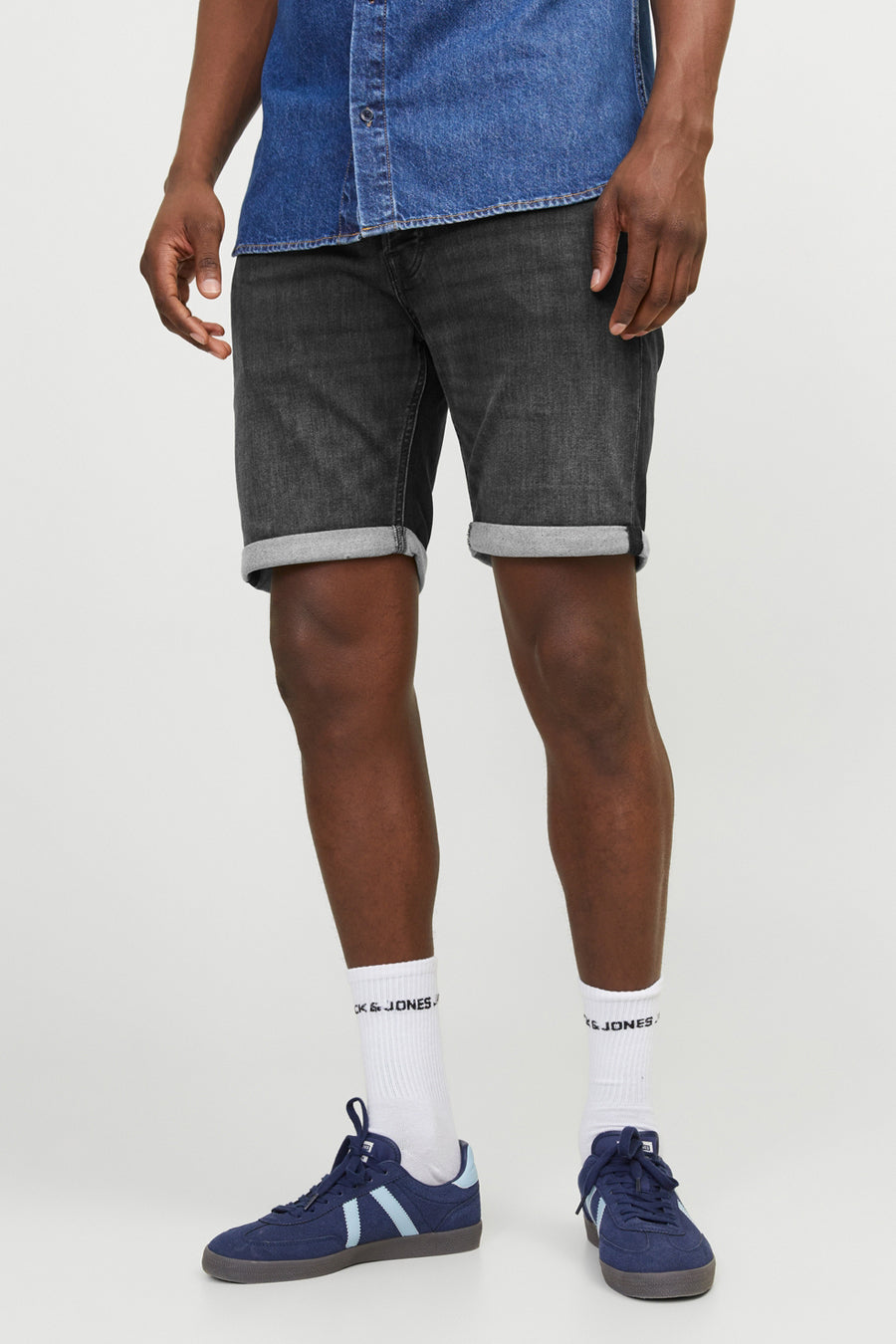 Zwarte spijkerbroekshorts van JACK & JONES JEANS INTELLIGENCE, gedragen met een spijkerblouse en marineblauwe sneakers.