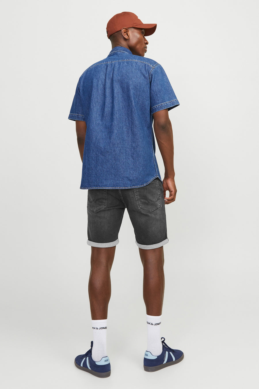 Korte zwarte denim van JACK & JONES JEANS INTELLIGENCE met omgeslagen zoom, gedragen met een overhemd en sneakers.