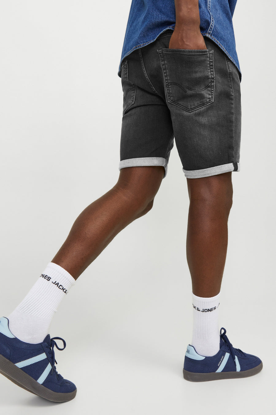 Korte zwarte denim van JACK & JONES, met opgerolde zomen en gedragen met witte sokken en blauwe sneakers.