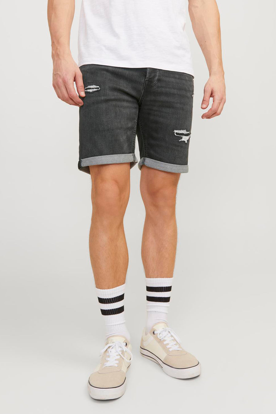 Korte zwarte denim van JACK & JONES JEANS INTELLIGENCE, met scheuren en opgerolde zomen, gedragen met gestreepte sokken.
