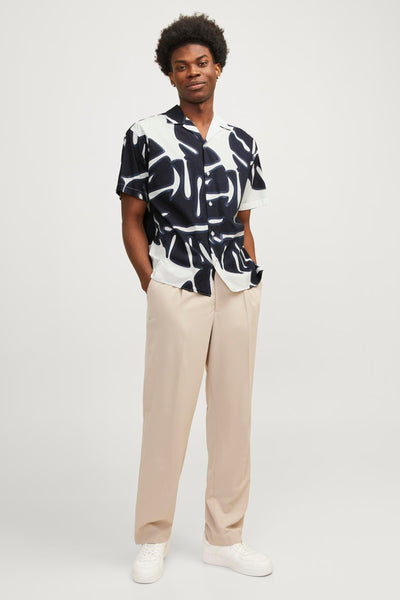 Chemise à manches courtes à motifs blanc et noir de PREMIUM by JACK & JONES, portée avec un pantalon beige.