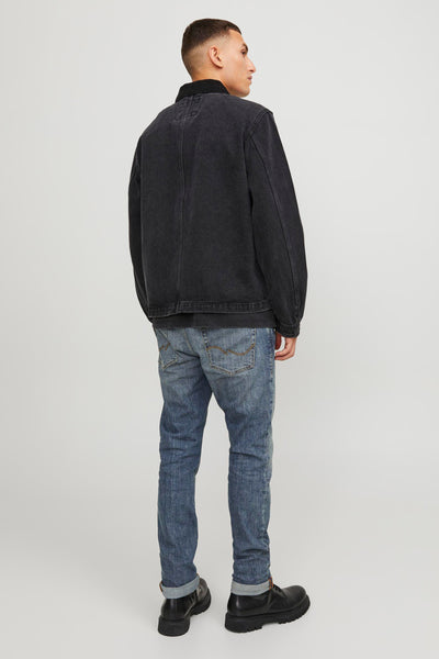 Jean slim bleu moyen de JACK & JONES JEANS INTELLIGENCE, porté avec une veste noire et des chaussures en cuir noir.