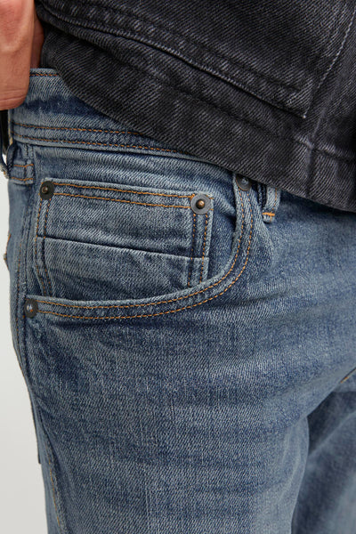 Jean slim bleu denim par JACK & JONES JEANS INTELLIGENCE, détail de poche avant, avec une veste en jean noire.
