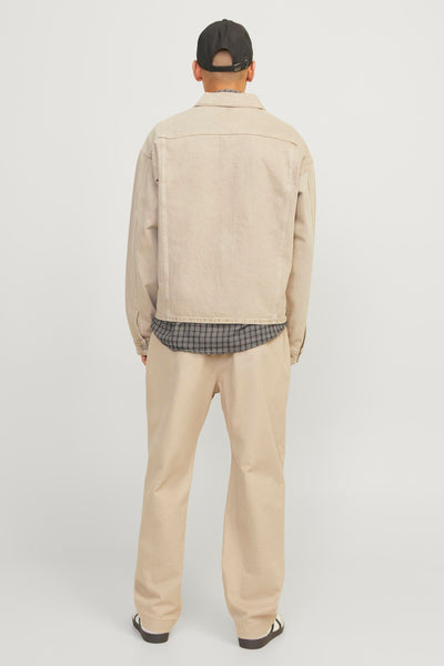 Pantalon écru JACK & JONES JEANS INTELLIGENCE, avec une coupe décontractée, porté avec une chemise à carreaux et une veste assortie.