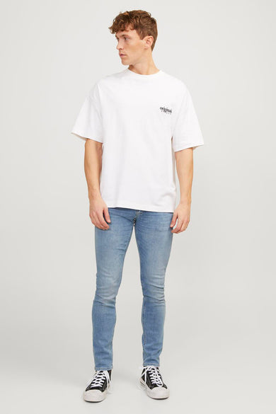 Jeans skinny bleu clair de JACK & JONES JEANS INTELLIGENCE, portés avec un t-shirt blanc et des baskets noires et blanches.