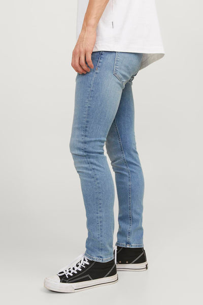 Jean skinny en denim bleu clair de JACK & JONES JEANS INTELLIGENCE porté avec un t-shirt blanc et des baskets noires.