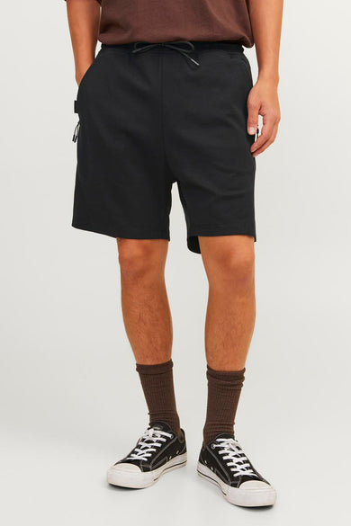 Short noir de JACK & JONES JEANS INTELLIGENCE, avec cordon de serrage, porté avec des chaussettes marron et des baskets noires.