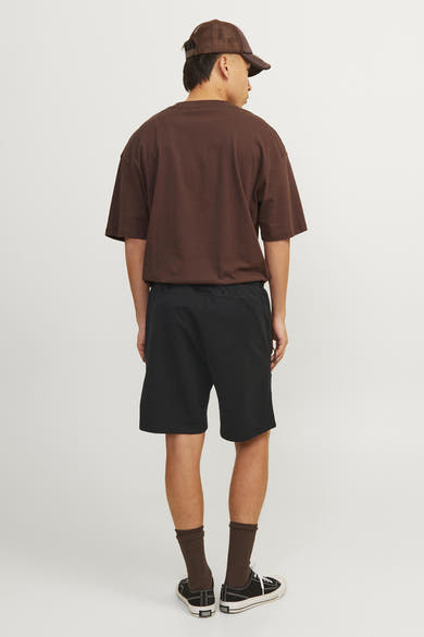 Korte zwarte broek van JACK & JONES JEANS INTELLIGENCE, gedragen met bruin T-shirt, zwarte sokken en schoenen.