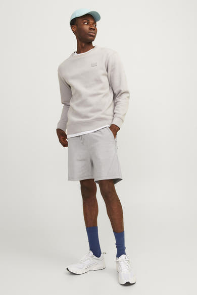 Grijze sportbroek van JACK & JONES JEANS INTELLIGENCE, gedragen met een lichtblauw sweatshirt en pet.